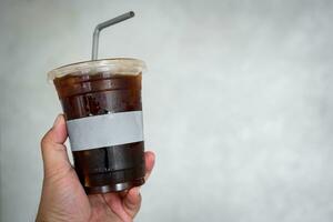 glacé noir café, homme en portant une Plastique verre de café photo