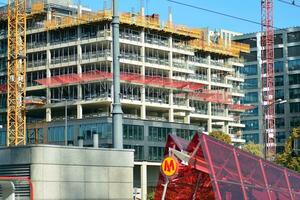 haute monter bâtiment en dessous de construction. installation de verre façade panneaux sur une renforcé béton structure. photo