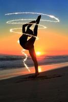 Jeune danseur qualifié à la plage pendant le coucher du soleil photo