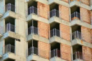 haute monter bâtiment en dessous de construction. installation de verre façade panneaux sur une renforcé béton structure. photo