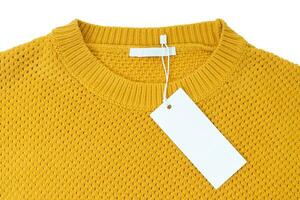 Étiquette de vêtements rectangulaire blanc blanc sur pull tricoté jaune isolé sur fond blanc photo