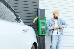 magnifique Jeune élégant homme est avec électrique voiture à jour mise en charge le véhicule photo