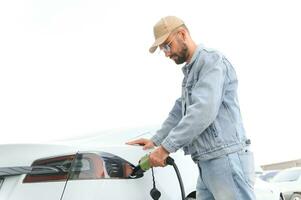 élégant homme inserts prise de courant dans le électrique voiture mise en charge prise photo