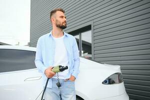 magnifique Jeune élégant homme est avec électrique voiture à jour mise en charge le véhicule photo