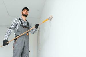 Jeune ouvrier La peinture mur dans chambre. photo