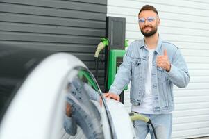 magnifique Jeune élégant homme est avec électrique voiture à jour mise en charge le véhicule photo