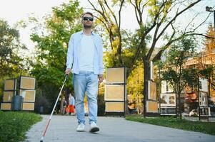 aveugle homme en marchant sur trottoir en portant bâton. photo