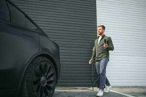 une homme des charges un électrique voiture photo