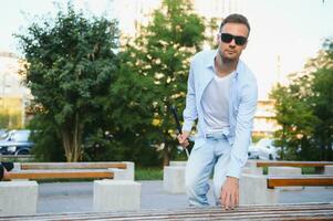 aveugle homme avec une en marchant bâton séance sur une banc à une parc photo