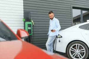 homme permanent par le sien électrique voiture photo