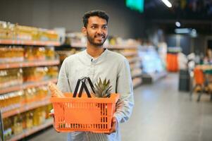 portrait de content Indien homme permanent dans de face de le produit compteur dans une épicerie magasin. homme achat épicerie pour Accueil dans supermarché. photo