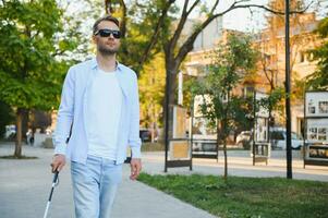 aveugle homme en marchant sur trottoir en portant bâton. photo