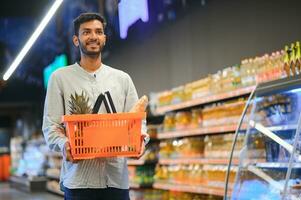 portrait de content Indien homme permanent dans de face de le produit compteur dans une épicerie magasin. homme achat épicerie pour Accueil dans supermarché. photo