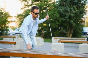 aveugle homme avec une en marchant bâton séance sur une banc à une parc photo