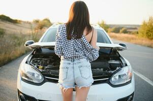 magnifique Jeune femme réparer le auto. le fille est permanent retour dans court shorts. photo