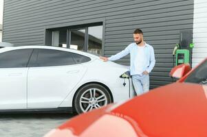 homme permanent par le sien électrique voiture photo