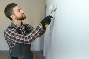 peintre La peinture une mur avec peindre rouleau. constructeur ouvrier La peinture surface avec blanc Couleur photo