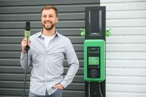 homme en portant Puissance mise en charge câble pour électrique voiture dans Extérieur voiture parc photo