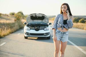 Jeune sexy femme avec cassé voiture appel sur le cellule téléphone. photo