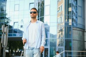 portrait de une jeune, Beau aveugle homme en marchant dans le ville. le concept de limité physique capacités. photo