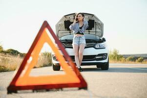 femmes parlant sur le téléphone à propos problème avec sa voiture elle ne peut pas. Jeune sexy fille consulte sur le téléphone pendant voiture réparation photo