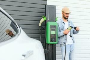 homme permanent par le sien électrique voiture photo