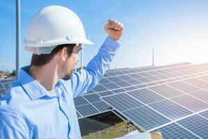 content ingénieur dans protecteur casque sur une solaire Puissance plante célébrer succès. photo