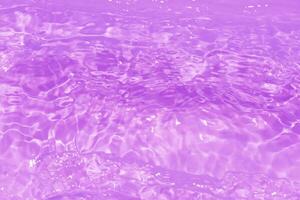 violet l'eau vagues sur le surface ondulations se brouiller. défocalisation flou transparent rose coloré clair calme l'eau surface texture avec éclaboussure et bulles. l'eau vagues avec brillant modèle texture Contexte. photo
