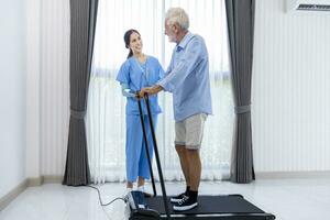 hospice infirmière est justificatif caucasien homme à marcher en utilisant tapis roulant dans le Pension retraite centre pour Accueil se soucier réhabilitation et Publier traitement récupération processus photo