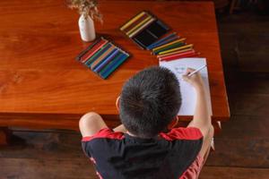 un garçon assis dans sa maison dessinant et peignant. photo