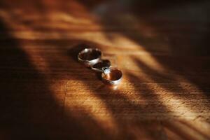 classique mariage anneaux sur une bois texture Contexte. une magnifique photo avec détails de le mariage. mariage journée. contour lumière. ombres et lumière