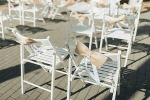 photo détails sur le voile. beaucoup blanc chaises sont décoré avec élégant doux rose arcs. mariage la cérémonie dans le cour. une luxueux mariage la cérémonie