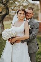 le la mariée avec une bouquet dans sa main dans le doux embrasse de le jeune marié. content mariage couple profiter leur fête. portrait de le la mariée et jeune marié. photo