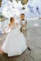 dans leur mains, le jeunes mariés tenir multicolore fumée bombes de bleu couleur. jeune marié et la mariée baiser. mariage amusement. photo