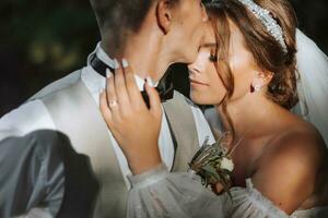 portrait de une magnifique couple dans l'amour sur votre mariage journée. une marcher dans le parc dans le lumière du soleil. incroyable baisers et câlins de le la mariée et jeune marié avec une bouquet photo