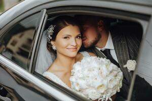 une moderne la mariée et jeune marié dans une dentelle robe dans une voiture la fenêtre. magnifique et souriant jeunes mariés. content vacances. photo