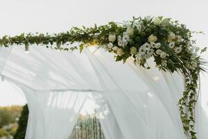 mariage la cérémonie par le lac. une luxueux mariage cérémonie. romantique mariage cérémonie. le présidium est décoré avec blanc fleurs. blanc chaises photo