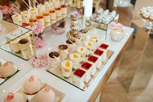 délicieux mariage accueil bonbons bar dessert table plein avec Gâteaux et bonbons et fleurs chinois Cerise fleurs sur le Contexte de un exquis restaurant photo