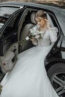 magnifique la mariée avec branché maquillage et coiffure dans luxe mariage robe dans noir mariage voiture séance sur retour siège et posant pour photographe photo