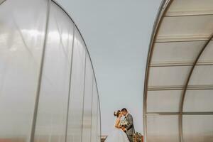 le la mariée et jeune marié contre le Contexte de le ciel. Royal mariage concept. le homme embrasse le la mariée entre grand arcs. tendresse et calme. photo