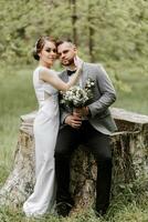 le la mariée dans une blanc soir robe pose avec le jeune marié avec une magnifique coiffure, le jeune marié doucement enveloppements le la mariée et penche contre sa coiffure photo