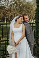 le la mariée et jeune marié penché leur épaules dans le parc. une couple de jeunes mariés, le la mariée et marié, à une mariage dans le la nature de vert des arbres. photo portrait mariage couple