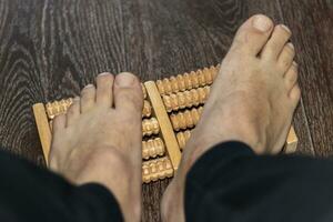 coup de le homme en utilisant pieds masseur à améliorer pied plat. soins de santé photo