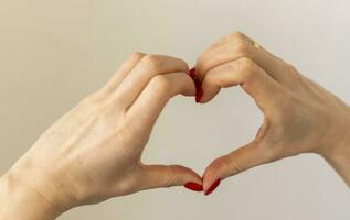 femme détient sa mains dans le forme de le cœur comme une symbole de l'amour. valentines journée photo