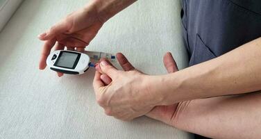 proche en haut coup de le glucomètre instrument sur le blanc surface. infirmière portion patient à vérifier sucre niveau. soins de santé photo