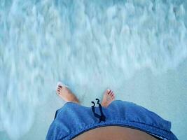 pieds de une homme sur plage le sable et mer l'eau. photo