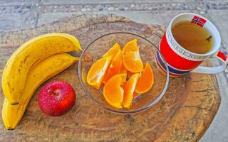 bananes tranché des oranges et rouge Pomme fruit et gingembre thé. photo