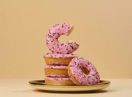 Donut couvert avec rose glaçage et saupoudré avec coloré arrose sur une rond assiette photo