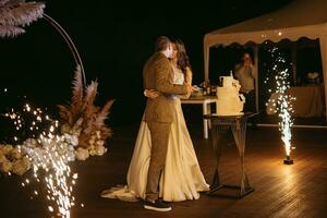 les jeunes mariés coupent et goûtent joyeusement le gâteau de mariage photo