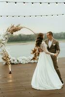 le premier mariage Danse de le la mariée et jeune marié sur le jetée près le rivière photo